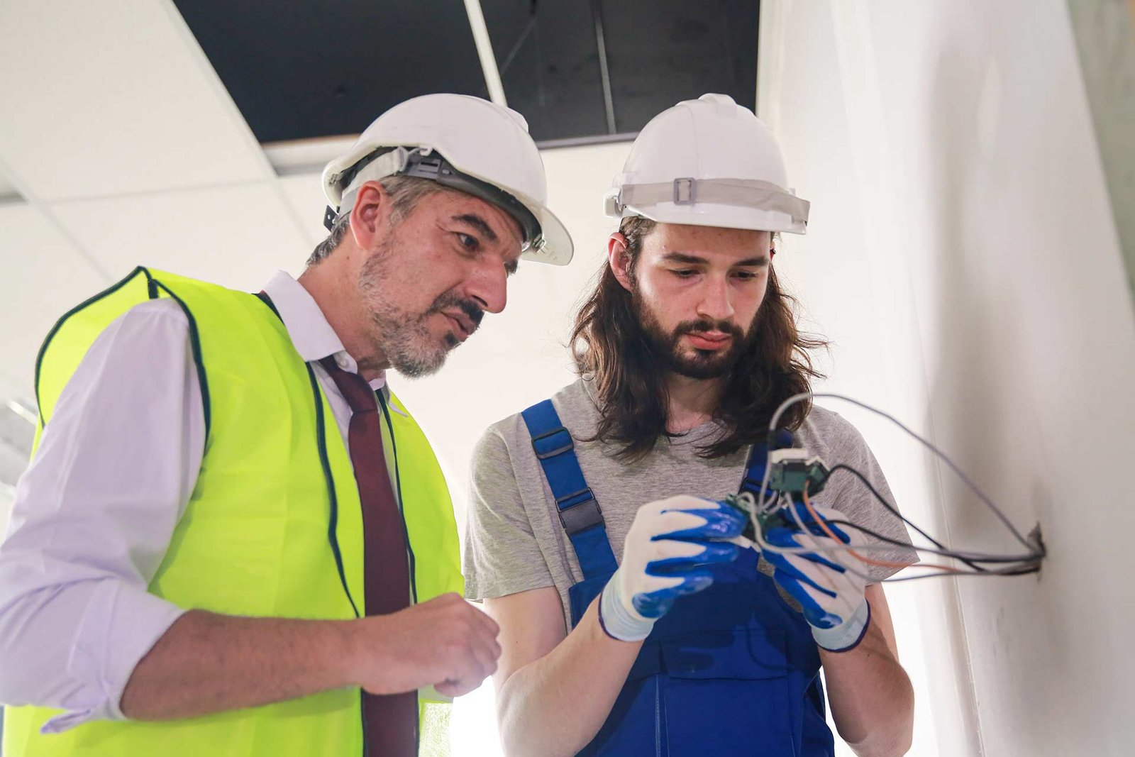 Técnico y aprendiz revisando un componente electrónico